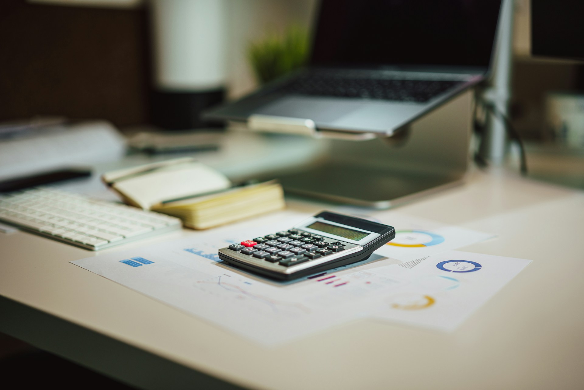 Calculator, financial documents, and laptop on a desk